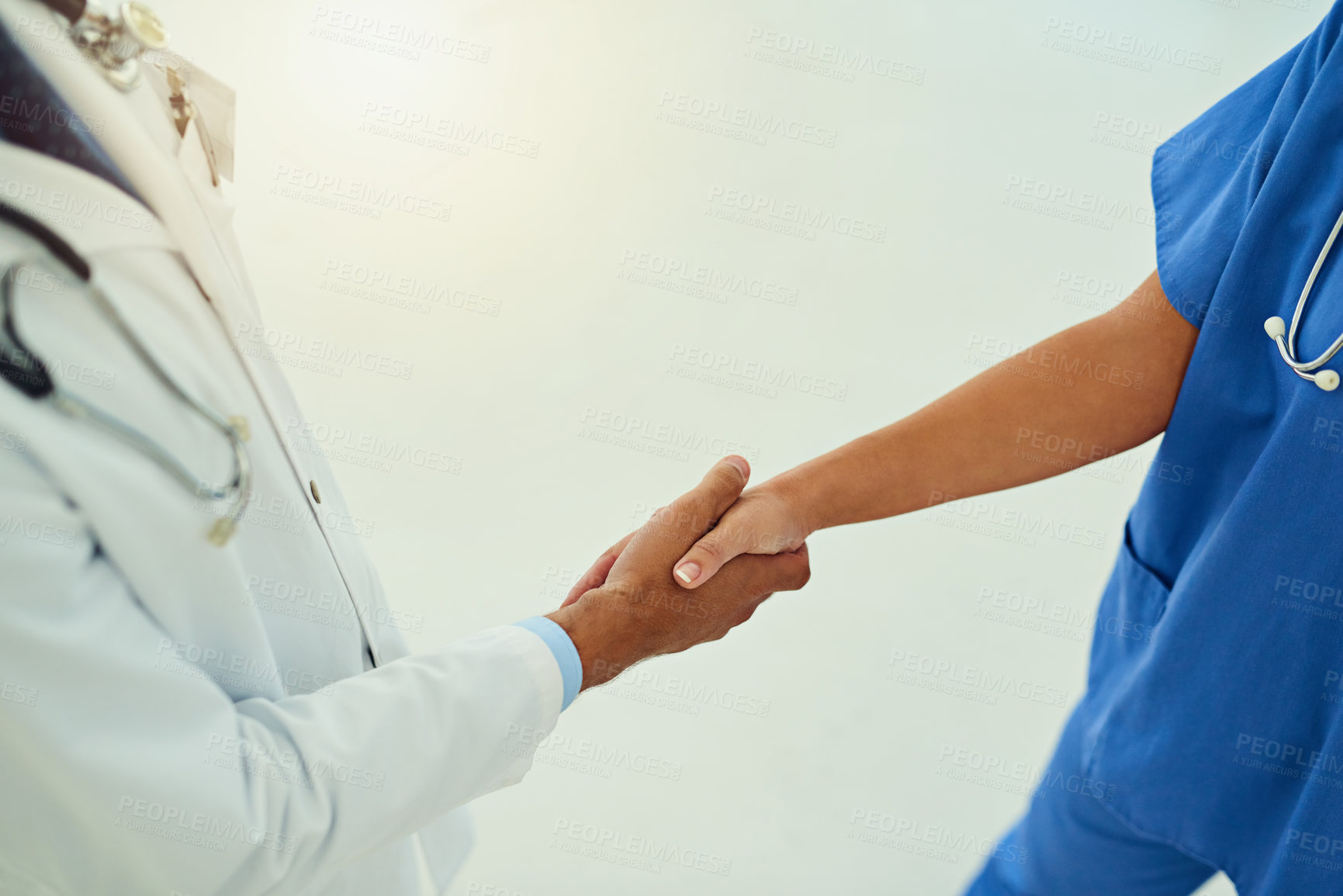 Buy stock photo High angle shot of two unidentifiable healthcare practitioners shaking hands in the hospital foyer