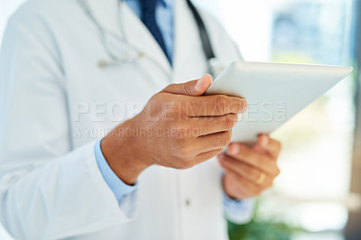 Buy stock photo Shot of an unidentifiable doctor checking a patient's medical records on his tablet