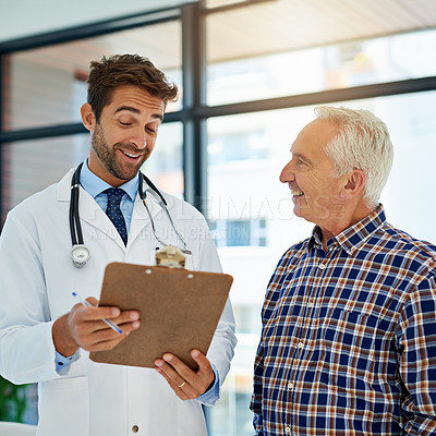Buy stock photo Shot of a cheerful doctor sharing good test results with his mature patient in the hospital