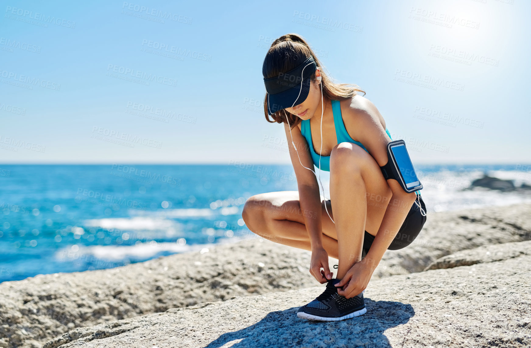 Buy stock photo Music, tying laces and health with woman in nature for start, performance and streaming podcast. Wellness, running and exercise with person and shoes at beach for fitness, marathon runner or training