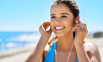 Buy stock photo Cropped shot of a young woman listening to music while out for a run by the sea