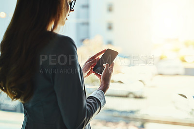 Buy stock photo Cropped shot of an attractive young businesswoman using her cellphone in the office