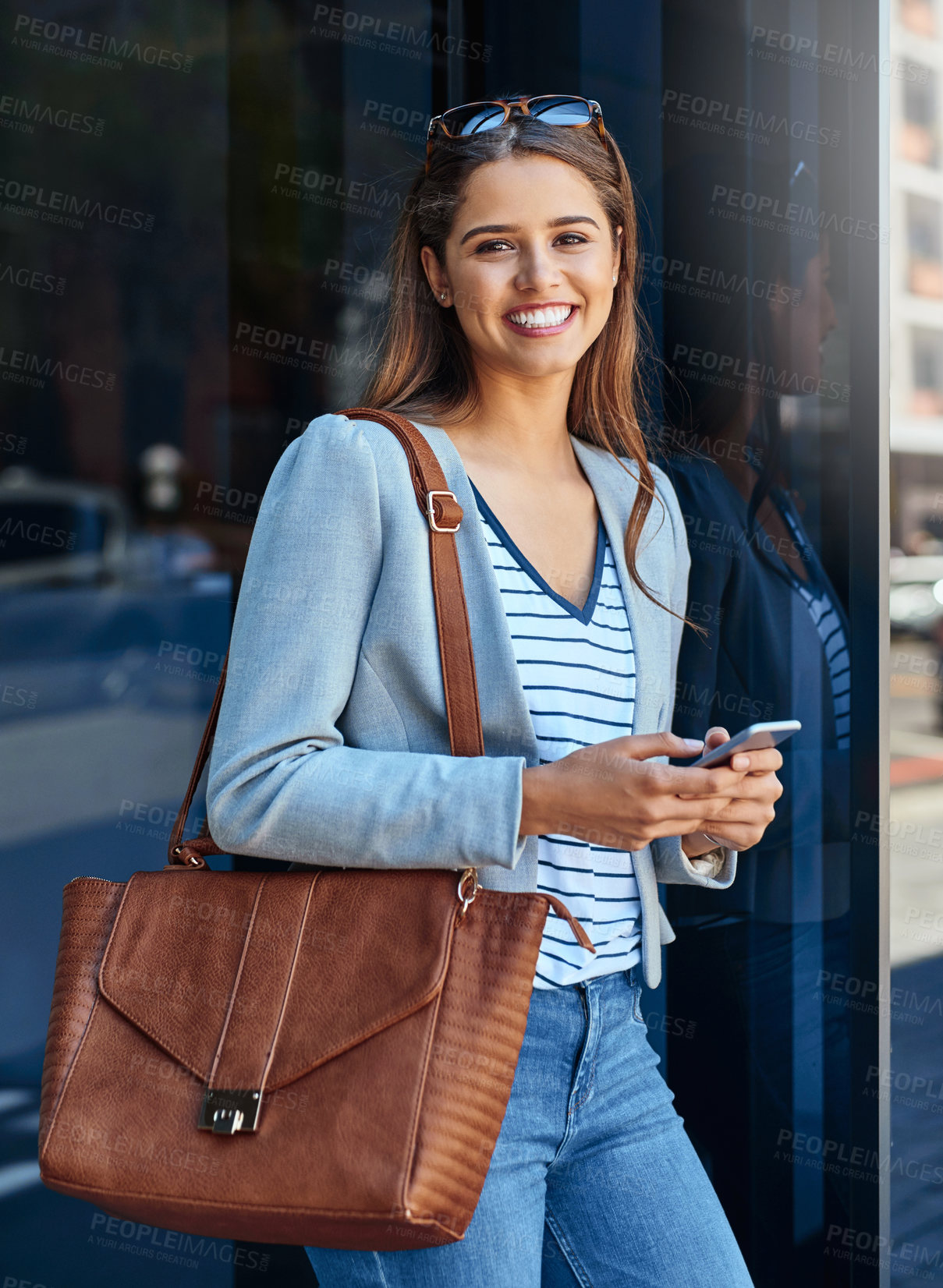 Buy stock photo Cropped portrait of an attractive young woman using her cellphone while leaving the office