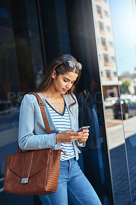 Buy stock photo Cropped shot of an attractive young woman using her cellphone while leaving the office