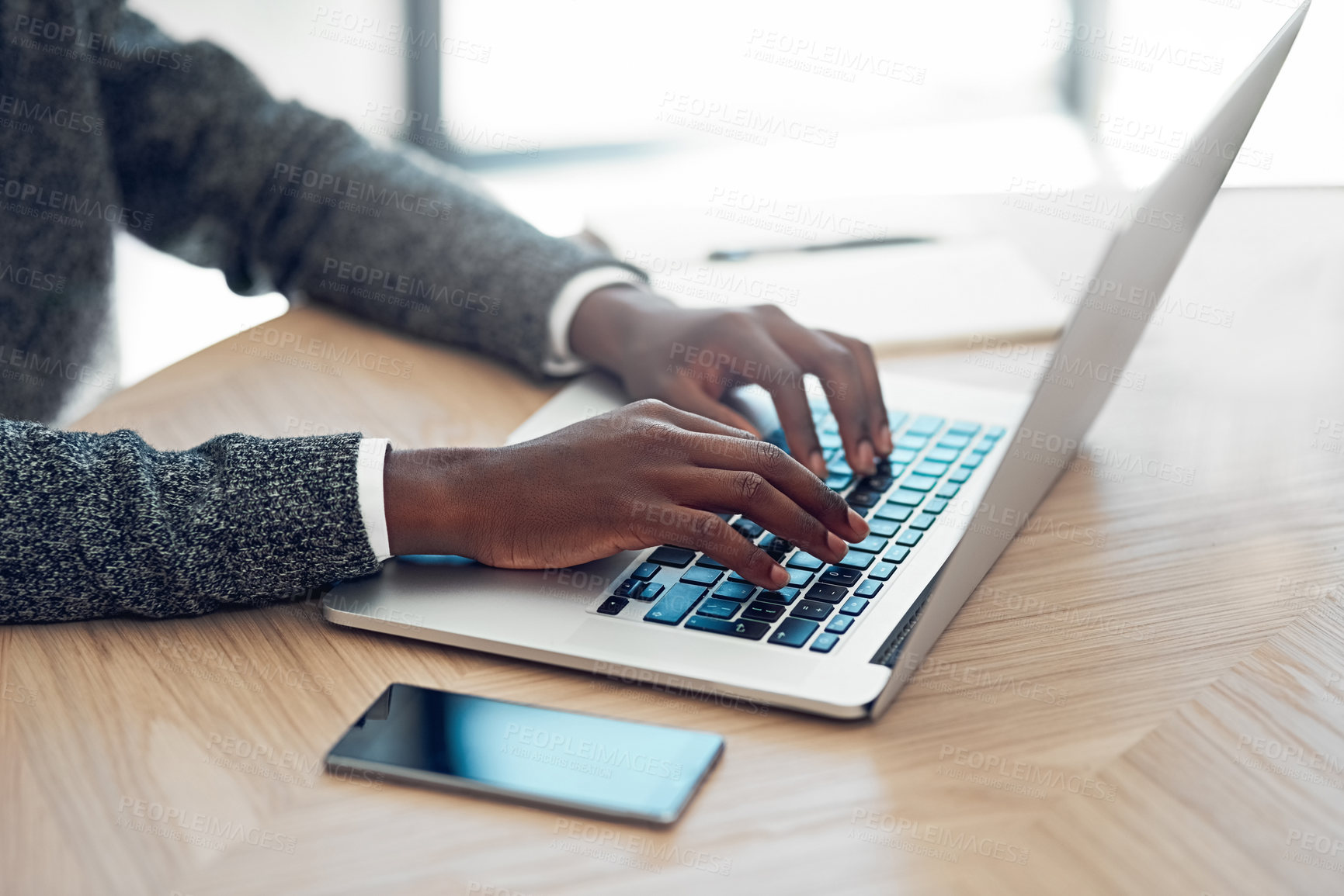 Buy stock photo Shot of an unidentifiable young businessman working on his laptop at a table in the office