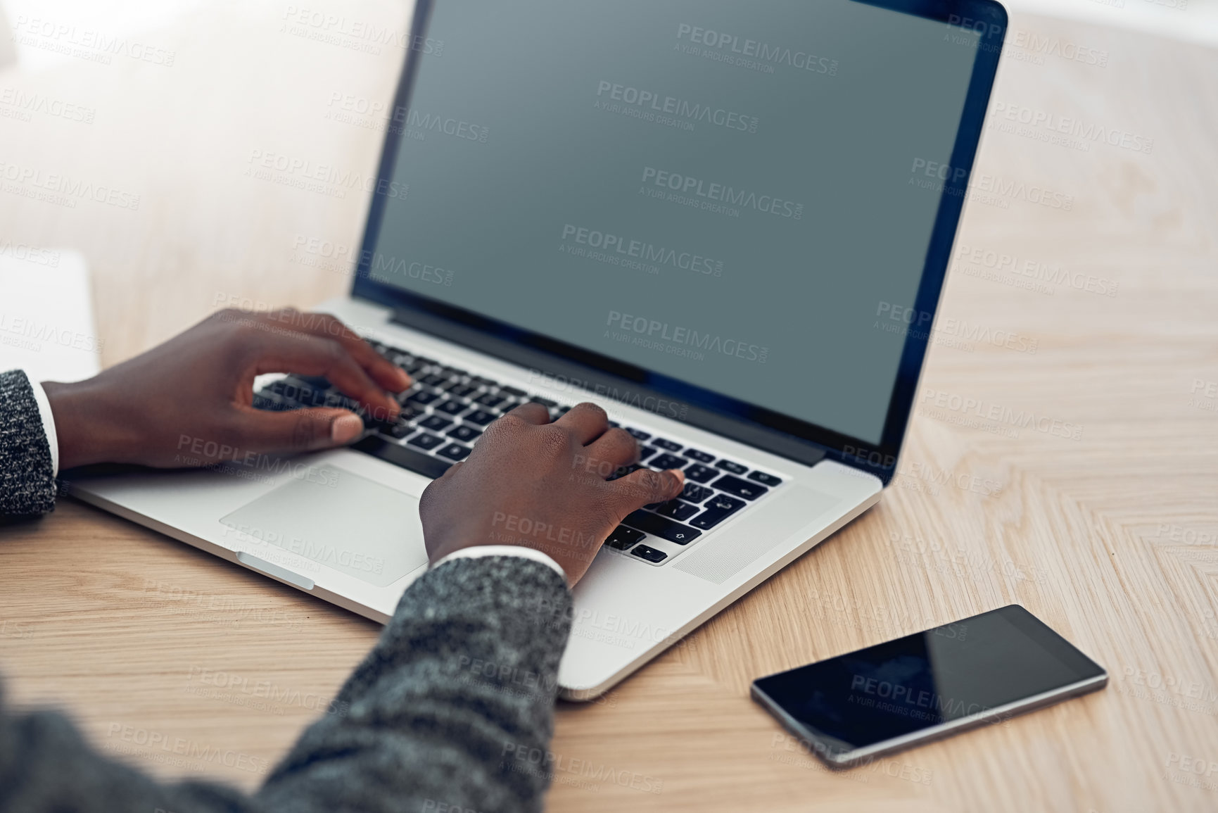 Buy stock photo Shot of an unidentifiable young businessman working on his laptop at a table in the office