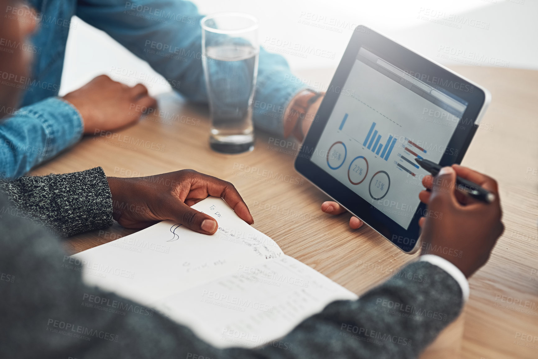 Buy stock photo Shot of two unidentifiable businessmen looking at graphs together on a tablet in the office