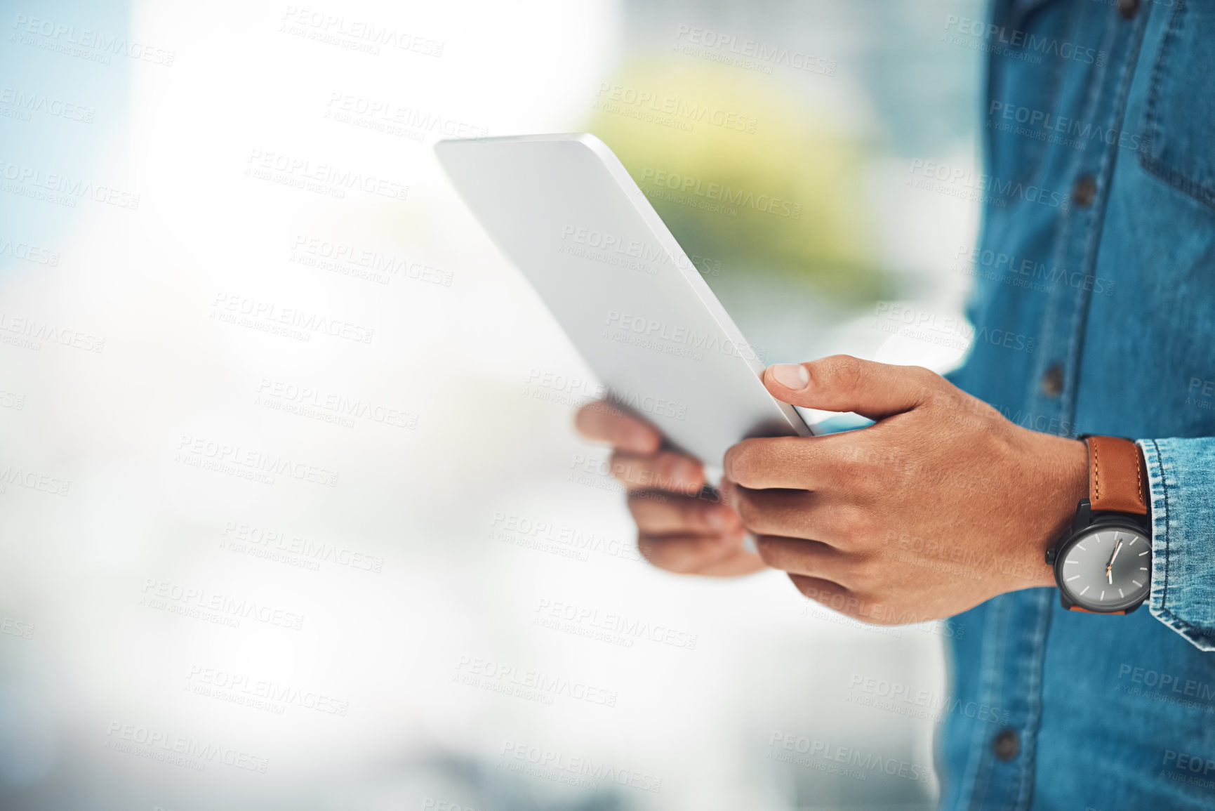 Buy stock photo Shot of an unidentifiable businessman using his tablet while standing in the office