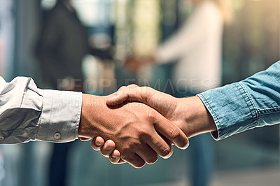 Buy stock photo Shot of two unidentifiable young business partners shaking hands in the office