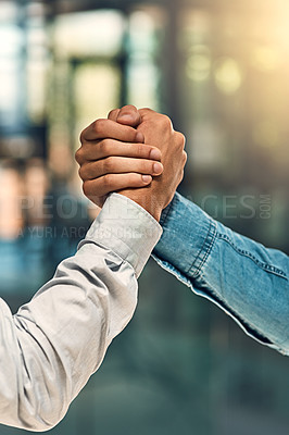 Buy stock photo Shot of two unidentifiable young business partners shaking hands in the office