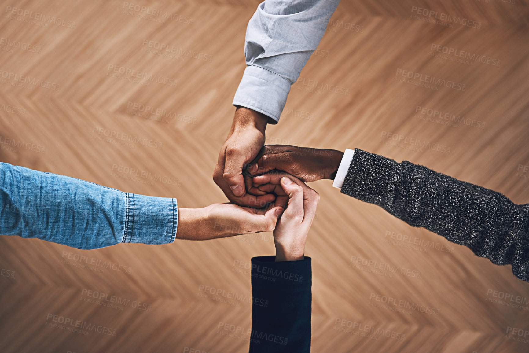 Buy stock photo High angle shot of a group of unidentifiable businesspeople joining their hands together in unity