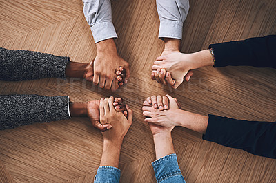 Buy stock photo High angle shot of a group of unidentifiable businesspeople holding hands together in unity