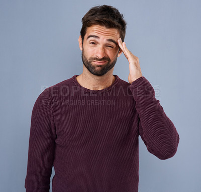 Buy stock photo Studio shot of a handsome young man suffering from a headache against a gray background