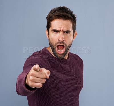 Buy stock photo Studio shot of a handsome young man pointing a finger in anger against a gray background