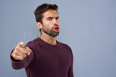 Buy stock photo Studio shot of a handsome young man pointing a finger in anger against a gray background