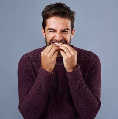 Buy stock photo Studio, scared and man bite nails or hands, thinking and anxiety for debt of student loans and stress. Blue background, fear and person with teeth to chew, frustrated and nervous of college in USA