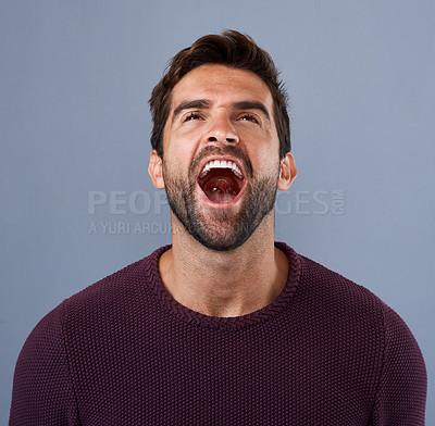 Buy stock photo Studio shot of a handsome young man screaming in anger against a gray background