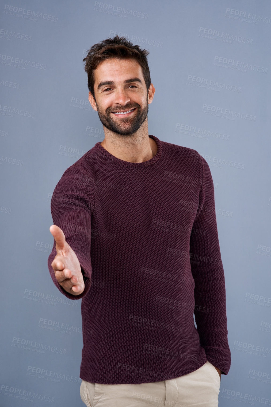 Buy stock photo Studio shot of a handsome young man extending his arm for a handshake against a gray background