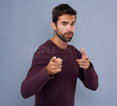 Buy stock photo Studio shot of a handsome young man with a cool attitude pointing against a gray background