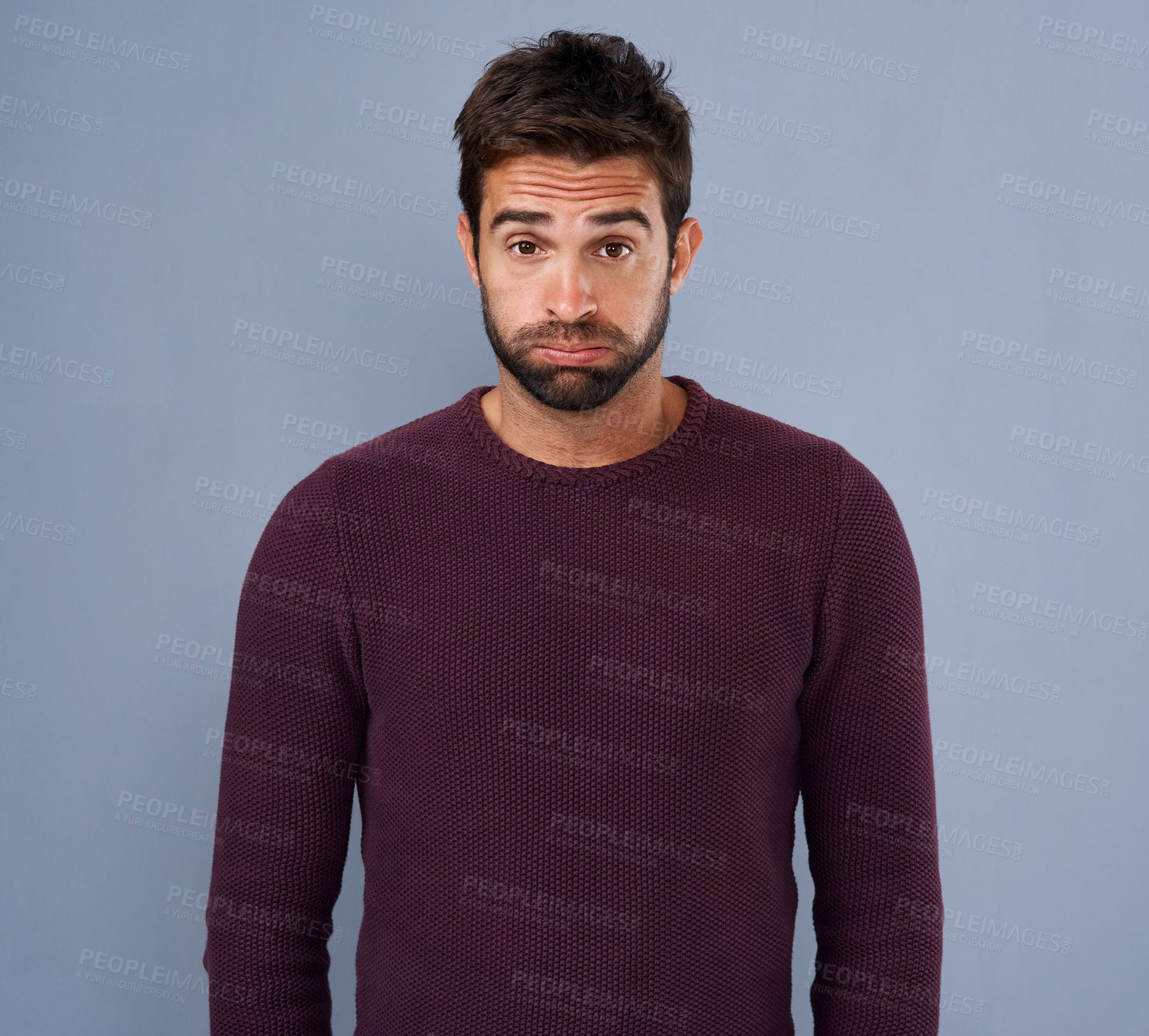 Buy stock photo Studio shot of a handsome young man looking uncomfortable against a gray background
