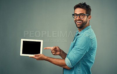 Buy stock photo Happy man, tablet and pointing to mockup screen for advertising against a grey studio background. Portrait of male person smiling showing technology display, chromakey or copy space for advertisement