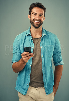 Buy stock photo Studio portrait of a handsome young man using a cellphone against a grey background