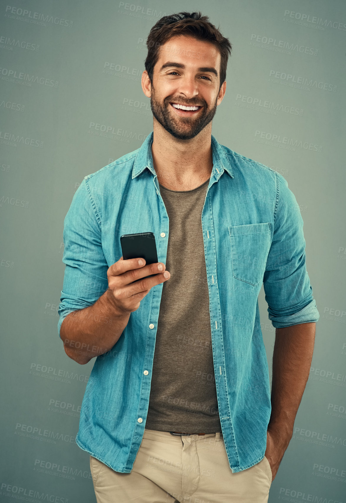 Buy stock photo Studio portrait of a handsome young man using a cellphone against a grey background