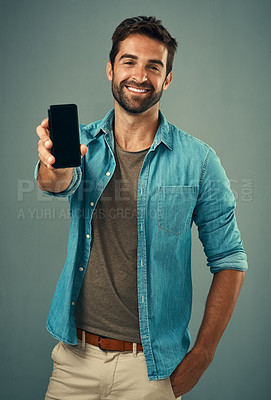 Buy stock photo Studio portrait of a handsome young man holding a cellphone with a blank screen against a grey background