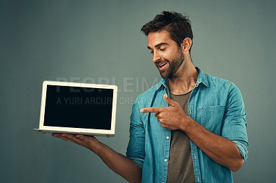 Buy stock photo Happy man, laptop and pointing to mockup screen for advertising or marketing against a grey studio background. Male person smiling and showing technology display or mock up space for advertisement