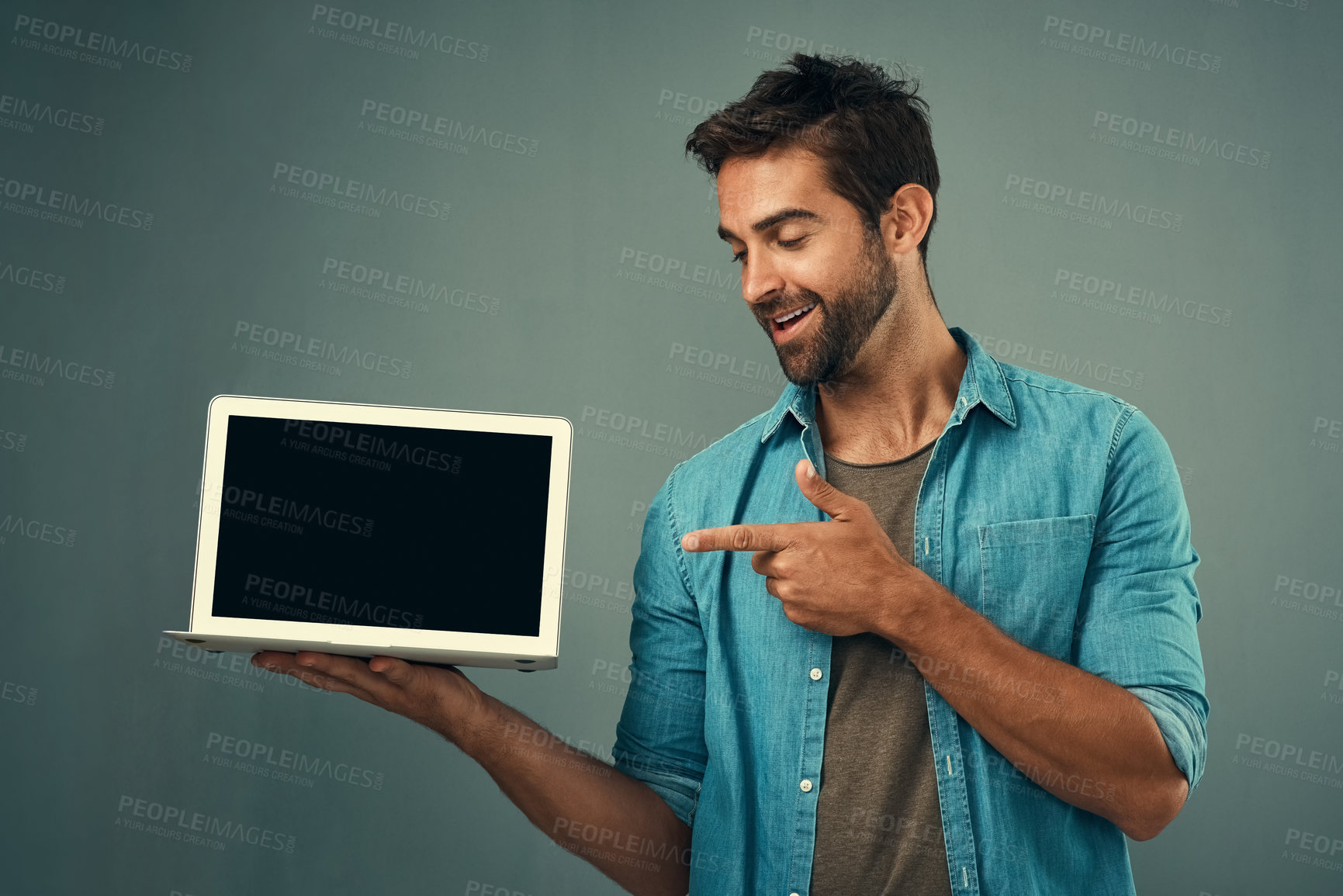 Buy stock photo Happy man, laptop and pointing to mockup screen for advertising or marketing against a grey studio background. Male person smiling and showing technology display or mock up space for advertisement