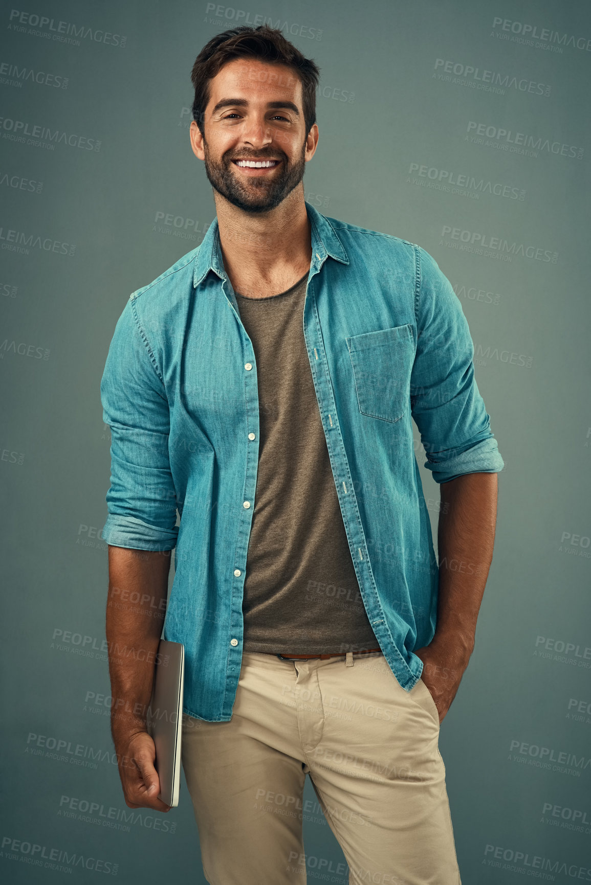 Buy stock photo Studio portrait of a handsome young man holding a laptop against a grey background