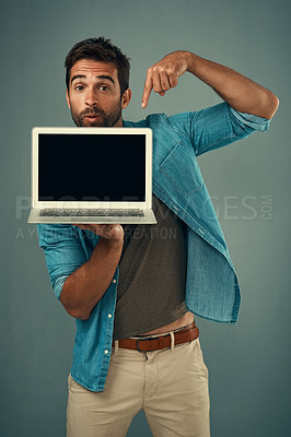 Buy stock photo Man, laptop and pointing on mockup screen for advertising or marketing against a grey studio background. Portrait of a male person showing computer display, mock up and tech space for advertisement