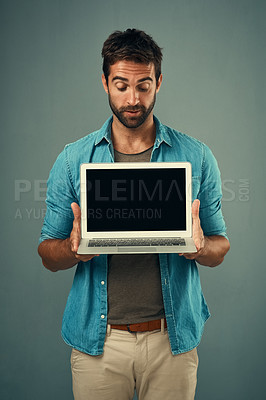 Buy stock photo Man, laptop and mockup screen for advertising or marketing against a grey studio background. Male person holding technology or computer display, mock up or copy space for branding or advertisement