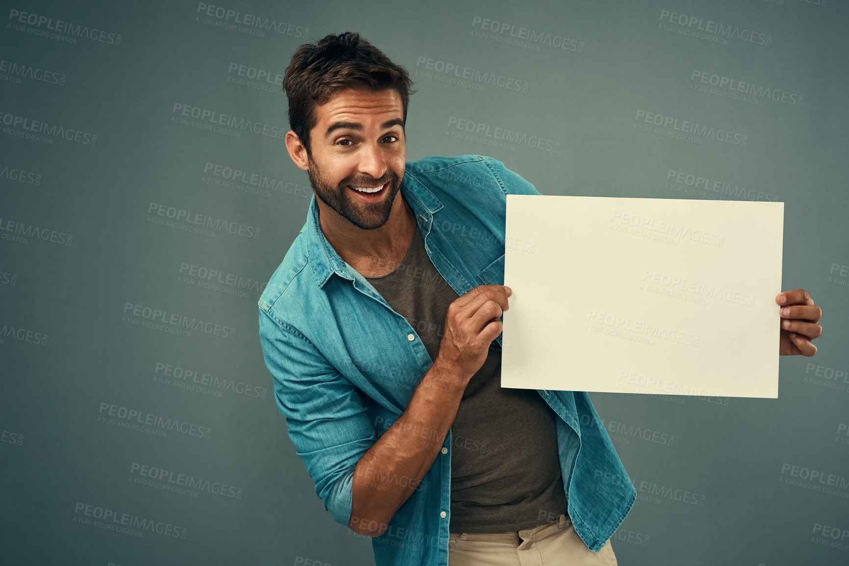 Buy stock photo Studio portrait of a handsome young man holding a blank placard against a grey background