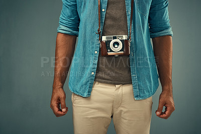 Buy stock photo Studio shot of a young man posing with a vintage camera around his neck against a grey background