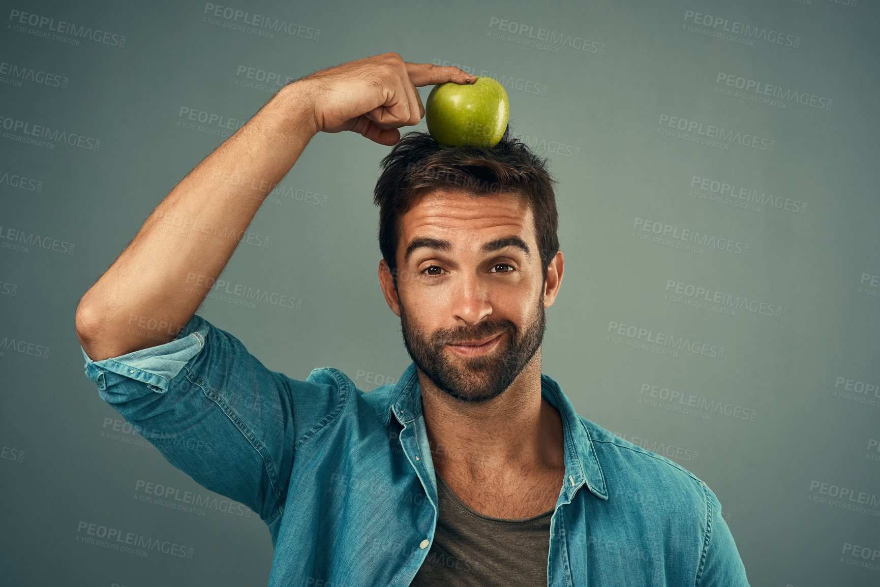 Buy stock photo Man, portrait and balance apple on head for healthy diet, wellness and natural organic food isolated on gray studio background. Fruit, face and person with nutrition target at breakfast for vitamin c