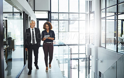 Buy stock photo Shot of two businesspeople having a discussion while walking together in an office