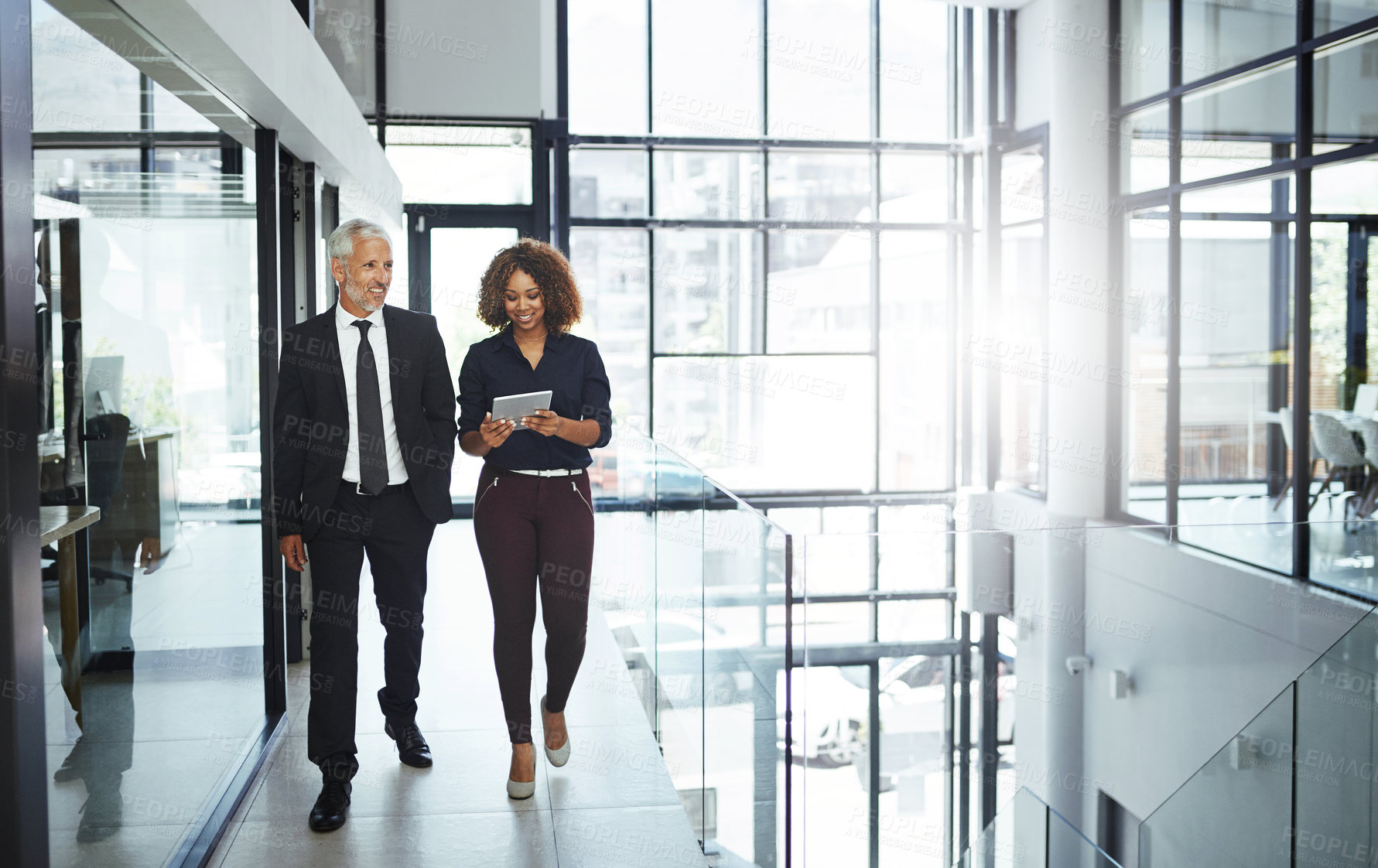 Buy stock photo Shot of two businesspeople having a discussion while walking together in an office