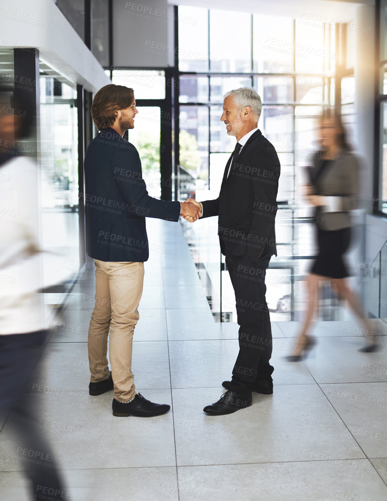 Buy stock photo Shot of two businessmen shaking hands in a busy office