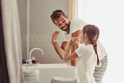 Buy stock photo Shot of a happy father and his little girl washing their hands together in the bathroom