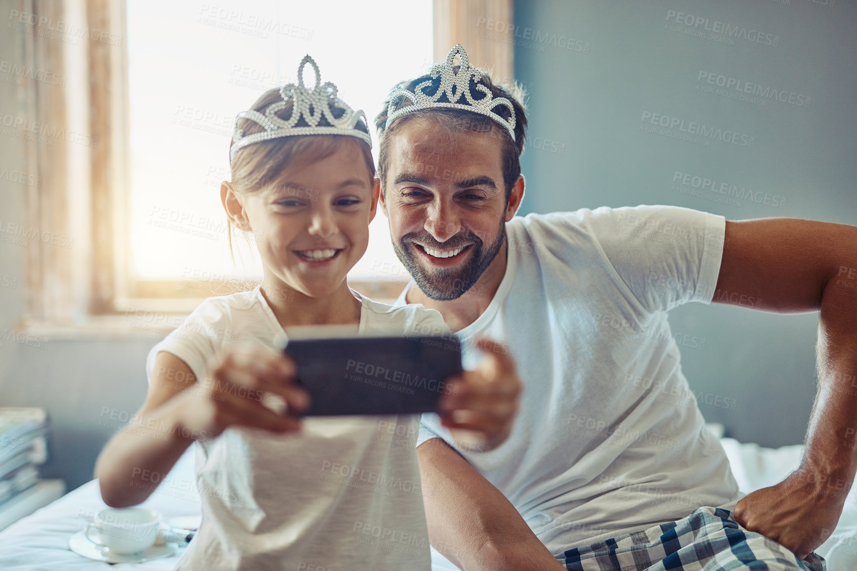 Buy stock photo Man, young girl and selfie in princess tiara, happiness with love and care at family home. Smile in picture, father and daughter bonding with crown, happy people spending time together in bedroom