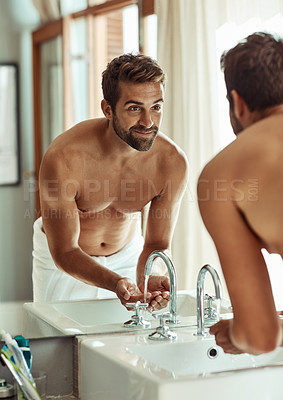 Buy stock photo Shot of a happy shirtless man rinsing his face by the bathroom sink