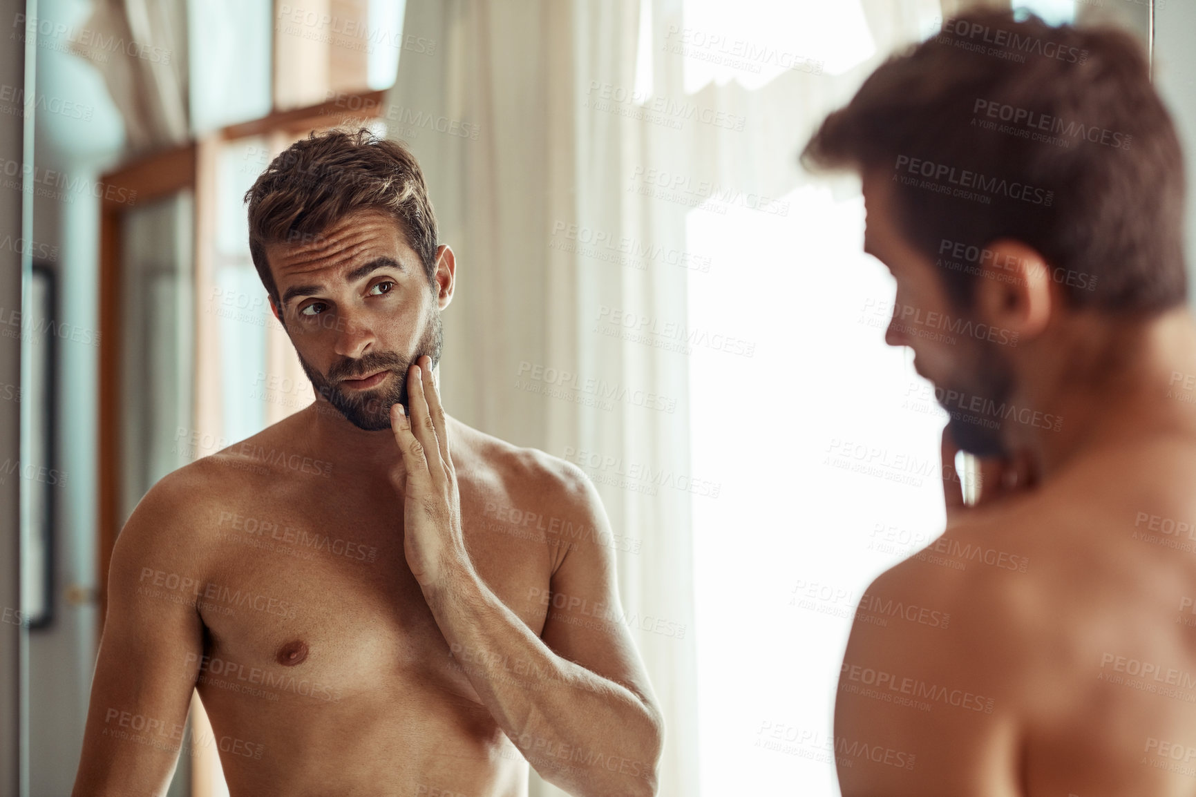 Buy stock photo Shot of a shirtless man checking out his skin in the bathroom mirror