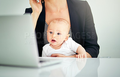 Buy stock photo Cropped shot of a businesswoman looking after her baby boy while working on her laptop