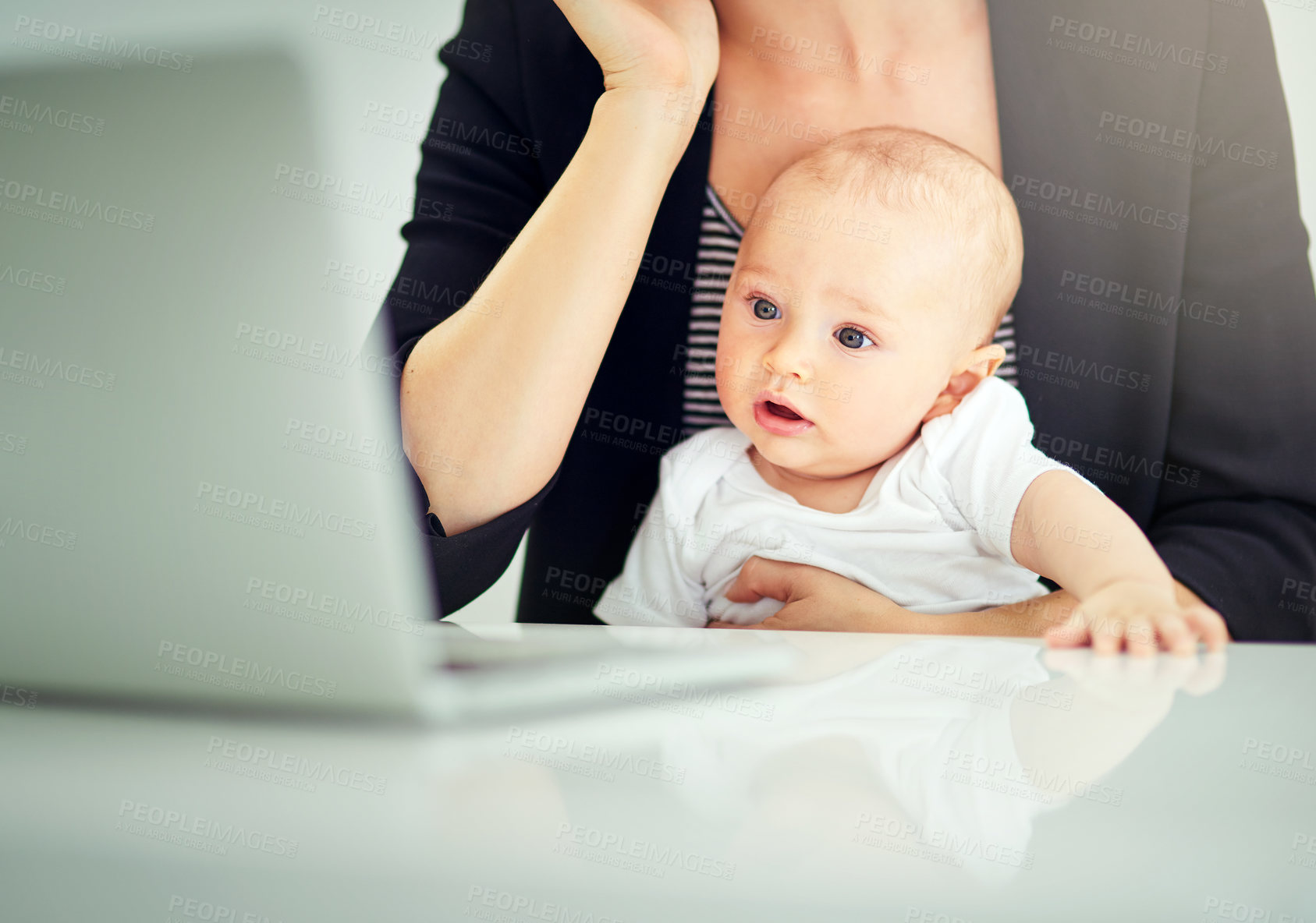 Buy stock photo Cropped shot of a businesswoman looking after her baby boy while working on her laptop