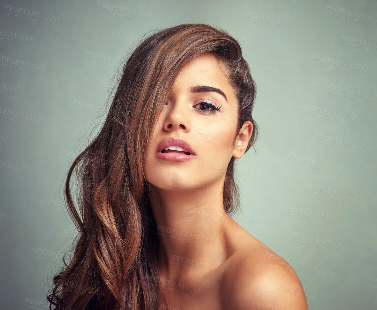 Buy stock photo Studio shot of a beautiful woman with long locks posing against a grey background