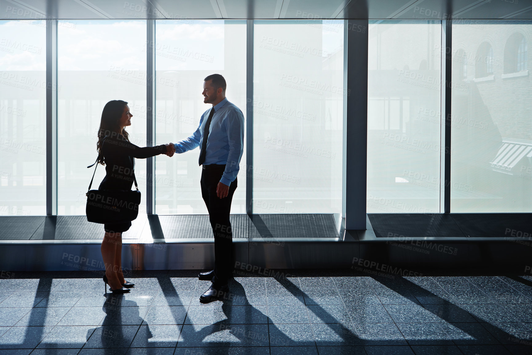 Buy stock photo Shot of two businesspeople shaking hands together in an airport