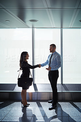 Buy stock photo Shot of two businesspeople shaking hands together in an airport