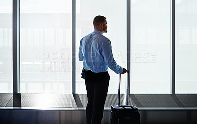 Buy stock photo Shot of a businessman looking through airport windows while on a business trip