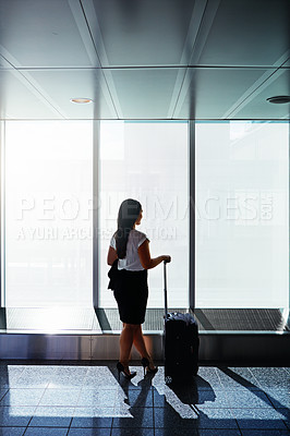 Buy stock photo Shot of a businesswoman looking through airport windows while on a business trip